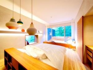 a bedroom with a bed and a window and pendant lights at 奥武雄温泉　風の森 in Ureshino