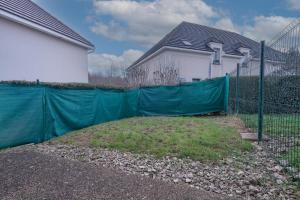 a green fence in front of a house at Maison Nova - à 8 minutes de Disneyland in Magny-le-Hongre