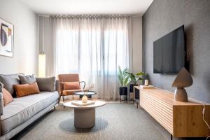 sala de estar con sofá y TV en Arrivo Apartments en Barcelona