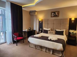 una habitación de hotel con una cama grande y una silla roja en Shadow Boutique Hotel & SPA, en Chişinău