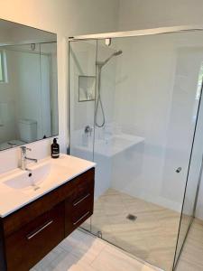 a bathroom with a shower and a sink and a mirror at Marie's Byron Getaway in Byron Bay