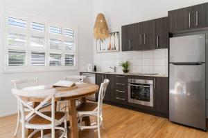 a kitchen with a wooden table and a stainless steel refrigerator at Marie's Byron Getaway in Byron Bay