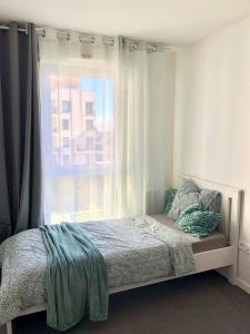 una camera con un letto e una finestra con un edificio di Chambre dans logement neuf, Paris, Disney, Centrex a Noisy-le-Grand
