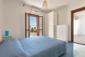 a white bedroom with a blue bed and a window at Villa Ilaria Chiusurelle by BarbarHouse in Porto Cesareo