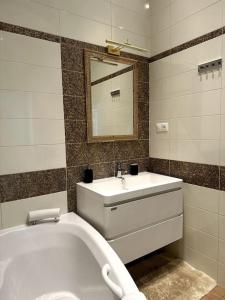 een badkamer met een bad, een wastafel en een spiegel bij Centrum Apartments Pstrossova in Praag