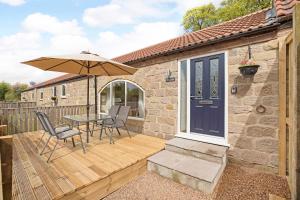 a wooden deck with a table and an umbrella at Tom's cabin in Knaresborough