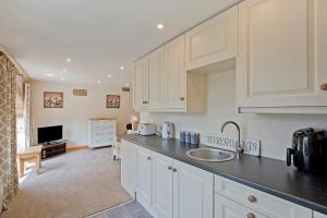 a kitchen with white cabinets and a sink at Tom's cabin in Knaresborough