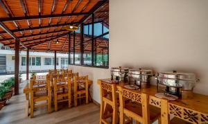 un restaurant avec des tables et des chaises en bois ainsi que des fenêtres dans l'établissement Treebo Trend 3C Comforts, à Chikmagalur
