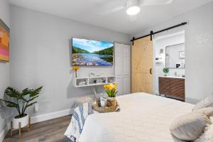 a white bedroom with a bed and a tv on the wall at Endless Sunset- Near Beach Surf and Pet Friendly in Huntington Beach