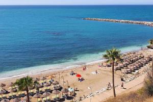 plaża z parasolami i ludzie na plaży w obiekcie Coqueto piso con Billar en Benalmadena Costa w mieście Benalmádena