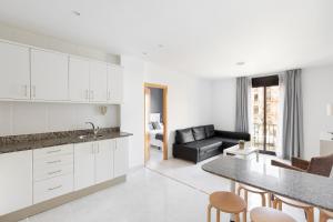 una cucina e un soggiorno con armadi bianchi e tavolo di Andreas Apartments a Tarragona