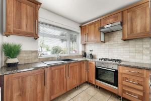 a kitchen with wooden cabinets and a stove top oven at Charming 3BR house with garden in Cambridge - Cherry Hinton in Cherry Hinton