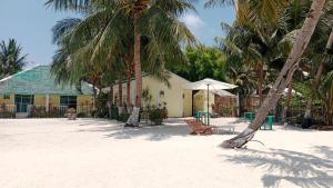 una playa con una silla, una sombrilla y palmeras en Ricks Mangrove Beach Resort, en Maricaban