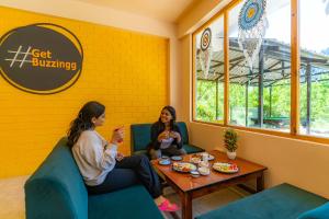 Zwei Frauen sitzen im Wartezimmer und essen Essen. in der Unterkunft ArtBuzz Manali in Manali