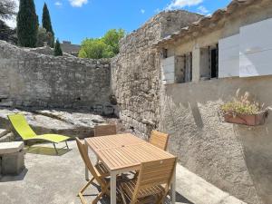 een patio met een houten tafel en stoelen voor een gebouw bij Chez Romain et Saphie in Les Baux-de-Provence