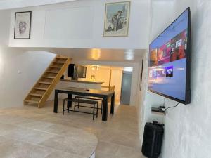 a living room with a dining room table and a flat screen tv at Chez Romain et Saphie in Les Baux-de-Provence