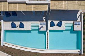 an overhead view of a swimming pool with blue water at Cora Hotel & Spa in Afitos