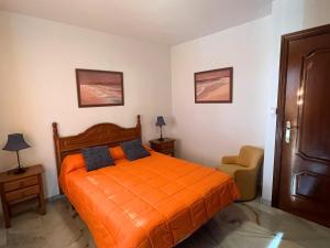 ein Schlafzimmer mit einem orangefarbenen Bett und einem Stuhl in der Unterkunft Casa María Pilar in Cazorla