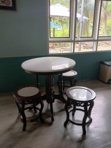 une table et deux tabourets devant une fenêtre dans l'établissement Fusion Villa, à Bedung