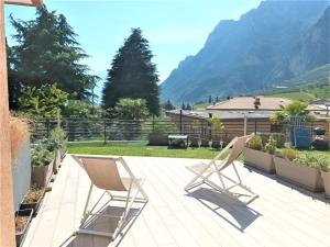 a pair of chairs on a patio with mountains in the background at 1Dest - Waterfall & Pool with Garden in Riva del Garda