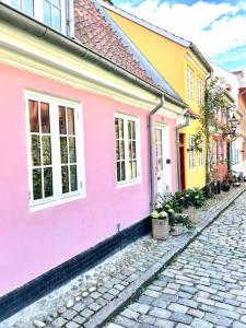 a cobblestone street with pink and yellow houses at Vidunderligt hus m/egen gårdhave - midt i centrum in Aalborg