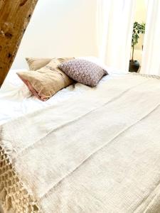 Una cama blanca con almohadas encima. en Vidunderligt hus m/egen gårdhave - midt i centrum, en Aalborg