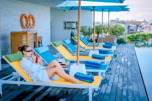 a woman sitting on a lounge chair at a resort at Rama Residence Padma in Legian