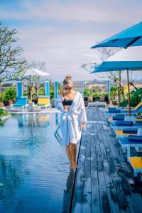 a woman standing in the water next to a swimming pool at Rama Residence Padma in Legian