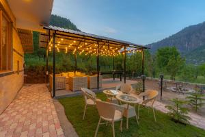 un patio con tavolo, sedie e luci di The Social Stays Manali formerly ArtBuzz a Manāli