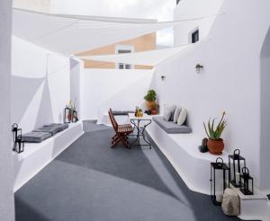 Habitación con paredes blancas, mesa y sillas. en Firalia, Casa in Rock Suites en Fira