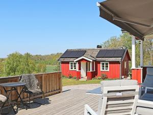een rode schuur met een tafel en stoelen op een terras bij 6 person holiday home in Sl inge in Slöinge