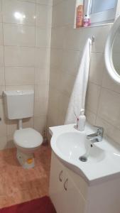a white bathroom with a toilet and a sink at Apartman Amela in Mostar +4 photos