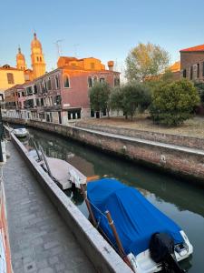 a boat with a blue tarp is parked in a canal at Due Delfini Apartment in Venice