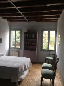 a bedroom with a bed and two chairs and windows at Due Delfini Apartment in Venice