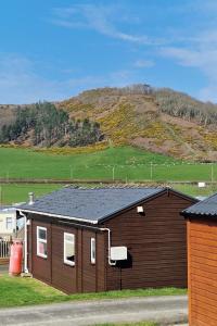 a brown house with a hill in the background at Chalet 88 in Aberystwyth
