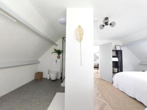 1 dormitorio en el ático con paredes blancas y 1 cama blanca en Guesthouse at the Amstel river with 2BR 2BA and garden, en Amstelveen
