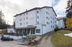 Un bâtiment blanc avec une voiture garée devant. dans l'établissement Apartment La Riva 105 Lenzerheide with an indoor Pool, à Lenzerheide