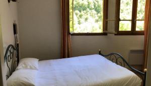 a bedroom with a white bed with a window at Hôtel-Bar l'Embarcadère in La Malène