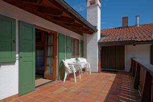 eine Terrasse mit einem Tisch und Stühlen auf einem Haus in der Unterkunft Kaffeehaus Kranzbach in Krün