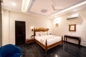 een slaapkamer met een bed en een blauwe stoel bij The Chronicles Hotel in Udaipur