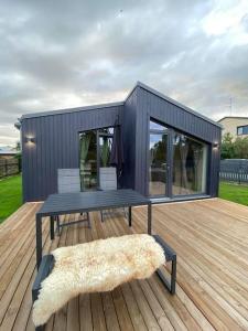 ein schwarzes winziges Haus mit einem Picknicktisch und einem Teppich in der Unterkunft EPA Brīvdienu mājiņa in Carnikava