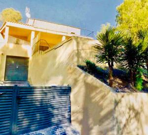 a house with a gate and a palm tree at Villa con piscina privada in Olivella