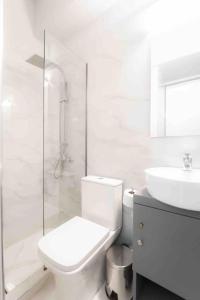a white bathroom with a toilet and a sink at Lux seaside apartment by Volos hospitality in Volos