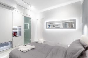 a white bedroom with a large bed and a mirror at Lux seaside apartment by Volos hospitality in Volos