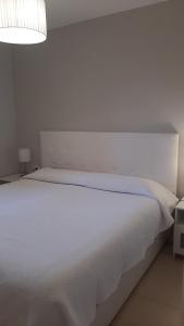 1 cama blanca en un dormitorio blanco con lámpara en Los Cancajos Apartamento Acijoa en Los Cancajos