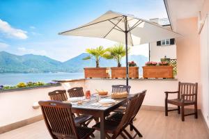 a table with chairs and an umbrella on a balcony at Residence Casa e Vela in Oggebbio