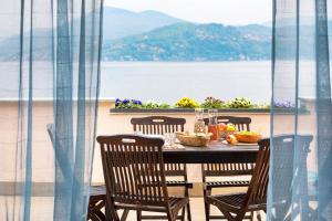 a dining table with chairs and a view of the water at Residence Casa e Vela in Oggebbio