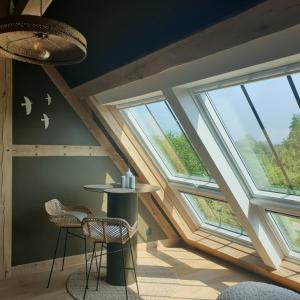 a room with large windows and two chairs and a table at Par Hasard ou pas in Saint-Martin-aux-Chartrains