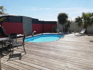 a swimming pool on a wooden deck next to a building at Studio indépendant chez l'habitant avec piscine et cuisine extérieure in La Rochelle