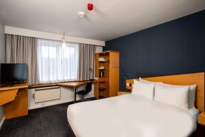 マンチェスターにあるホリデイ イン エクスプレス マンチェスター - ソルフォード キーズの大きなベッドとデスクが備わるホテルルームです。
